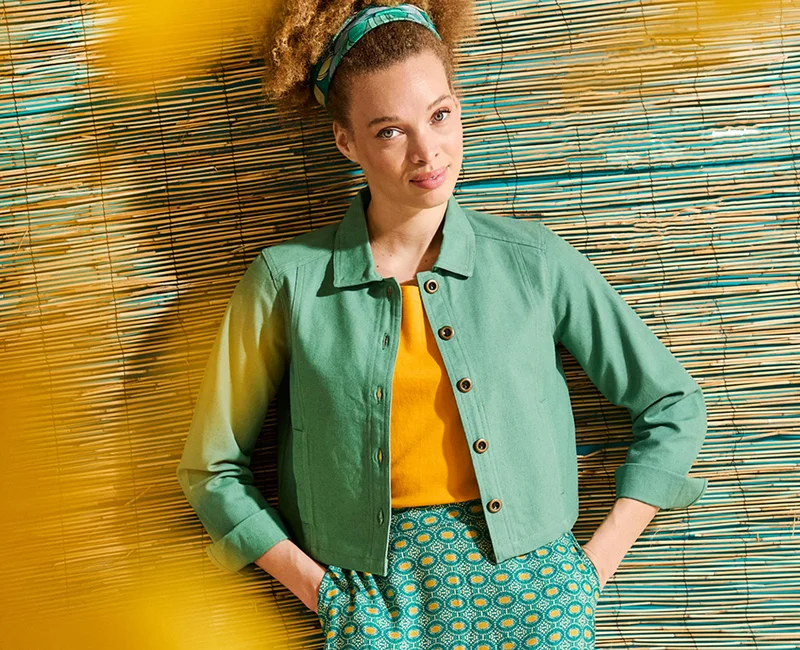Model met turquoise jasje, geel shirt en broek in turquoise en gele print