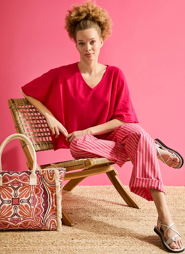 Model met rose gebreide zomertrui en rose broek met witte strepen voor de merkpagina over La Fiancée