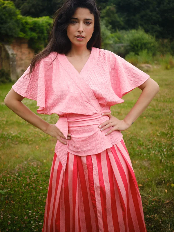 Model met roze wrap top en wijde retrostijl rok met roze en rode strepen