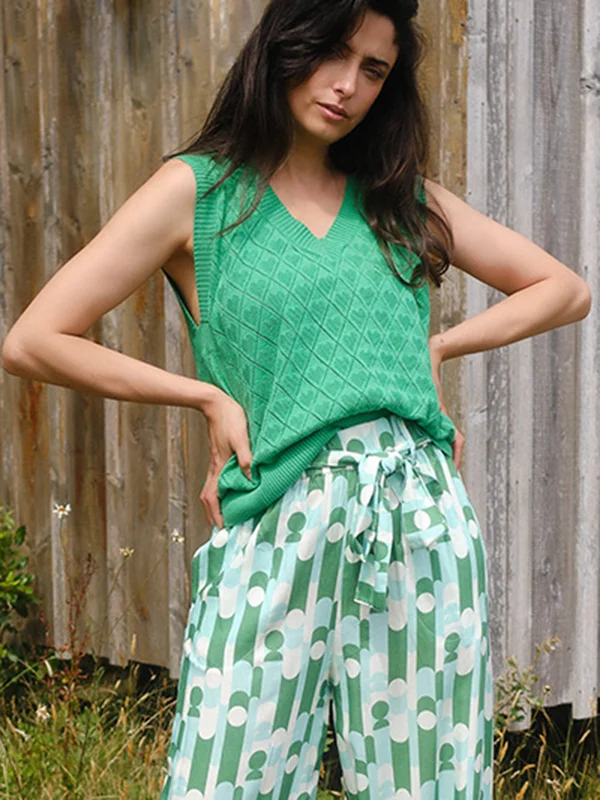 Model met groene gebreide mouwloze top en broek in wit, groene, turquoise retroprint