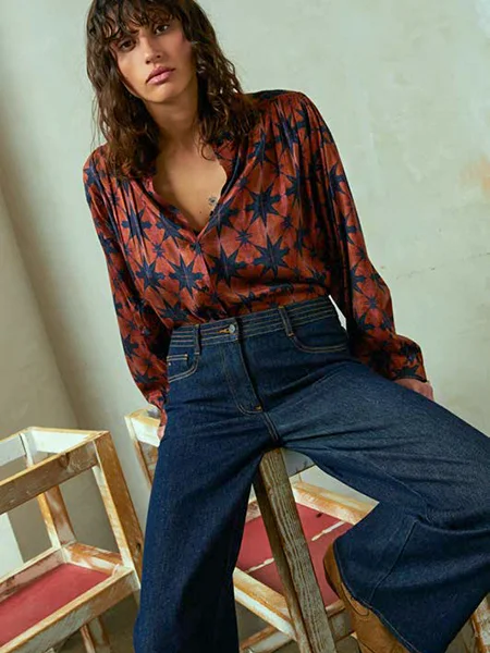 Model draagt roestbruine blouse met blauwe sterrenprint gecombineerd met een donkerblauwe spijkerbroek van het duurzame merk Andam