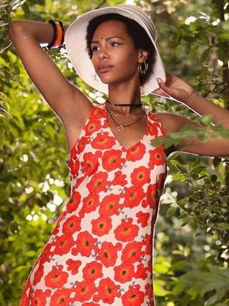 Model draagt kleurrijk Kali-Yog jurkje met rode bloemen van biologisch katoen