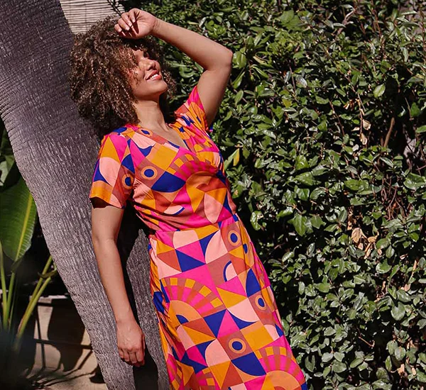 Model met rose gebreide zomertrui en rose broek met witte strepen voor de merkpagina over La Fiancée