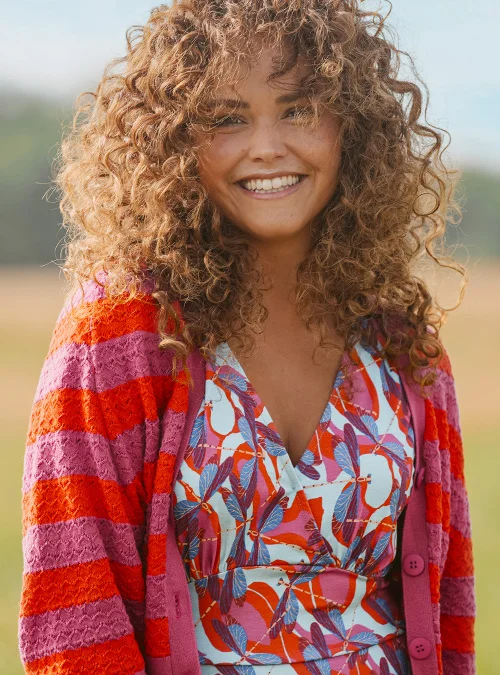 Model met kleurrijke zomerjurk en rood roze gestreept vestje