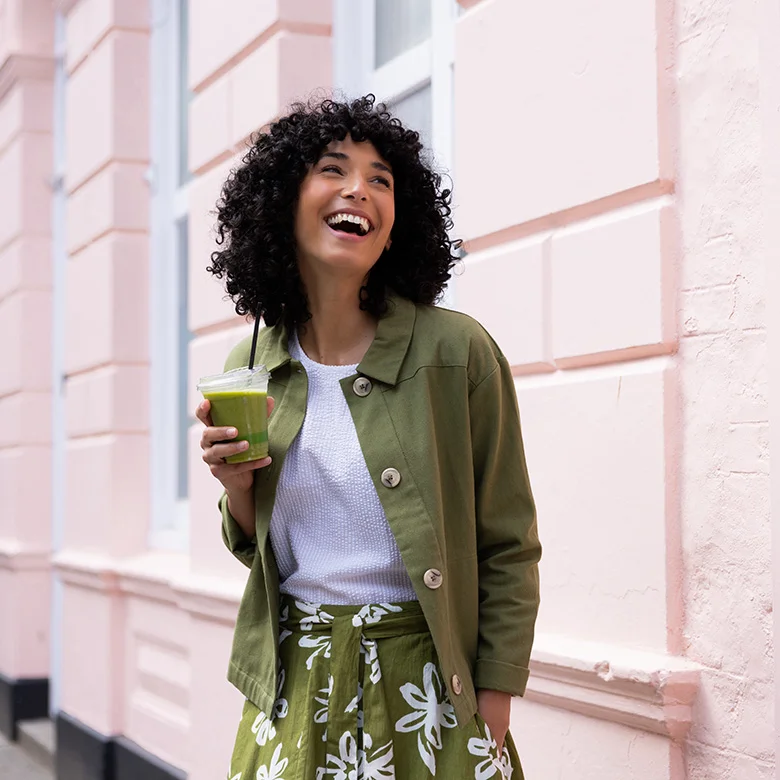 Model met groen jasje, wit shirt en groene rok met witte bloemen uit de zomercollectie van Nomads
